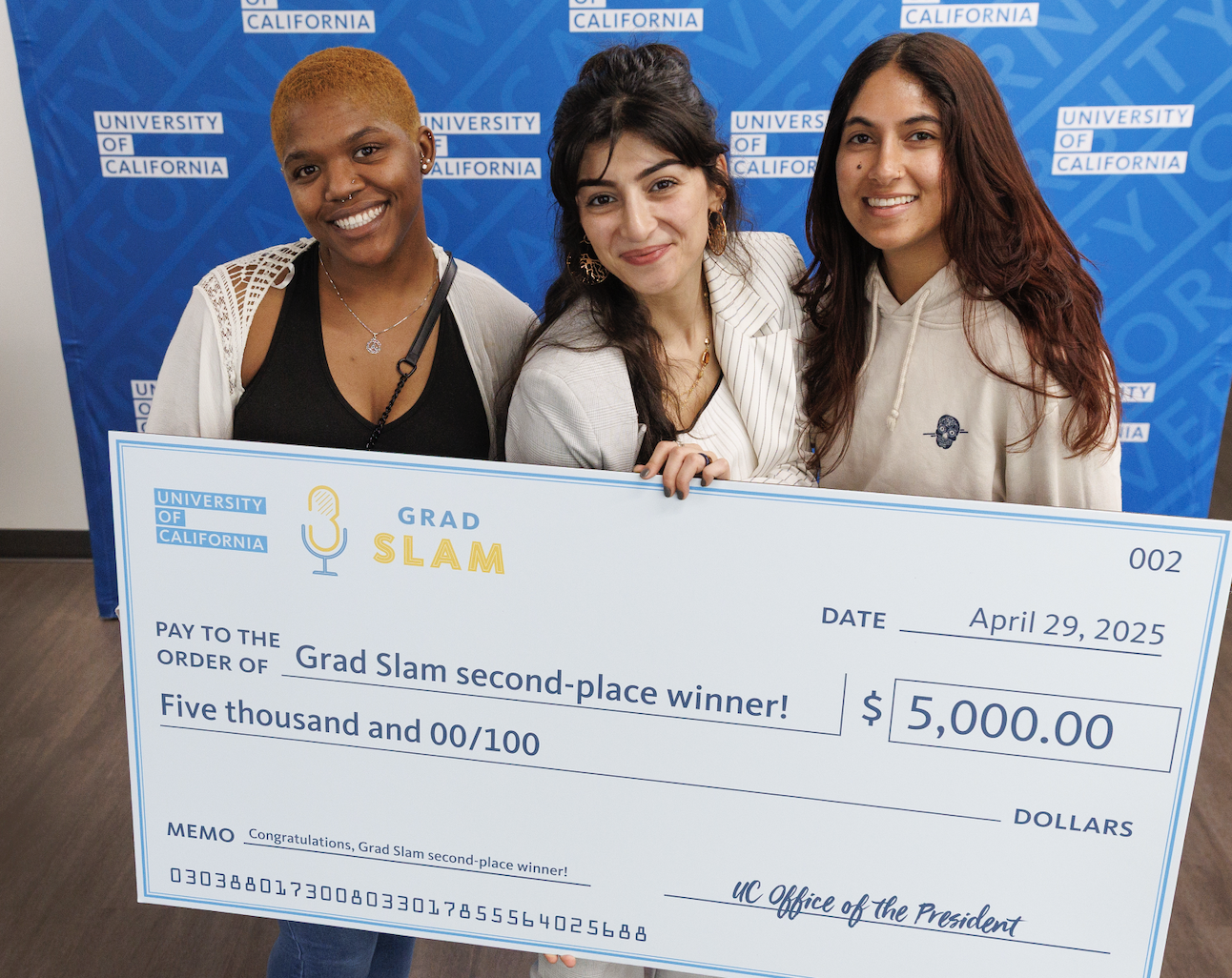 Yara Khatib smiling with giant check and Olsen lab mates in front of a UC backdrop (Robert Durell, University of California).