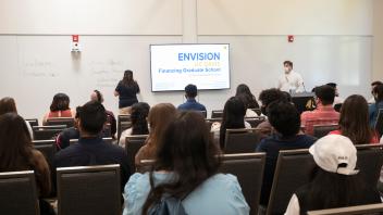 Envision students in lecture room during a presentation. Presentation on the screen entitled "ENVISION UC DAVIS: Financing Graduate School"