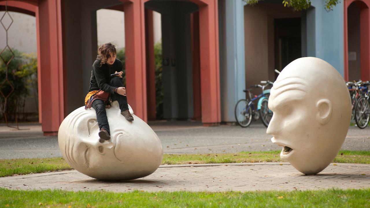 A student sits on an Yin and Yang Egghead and the head appears to look up at her on Tuesday November 27, 2012 at UC Davis.