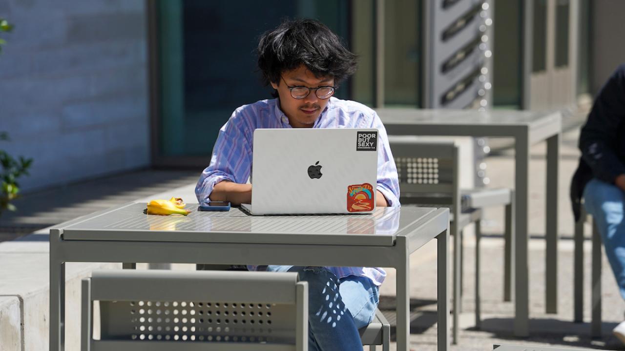 Student at table looking at computer.