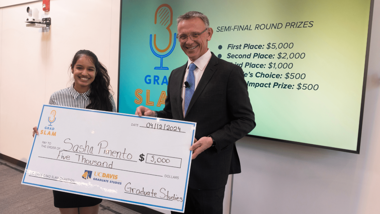 Sasha Pimento posing with Dean Jean-Pierre Delplanque with her winning check