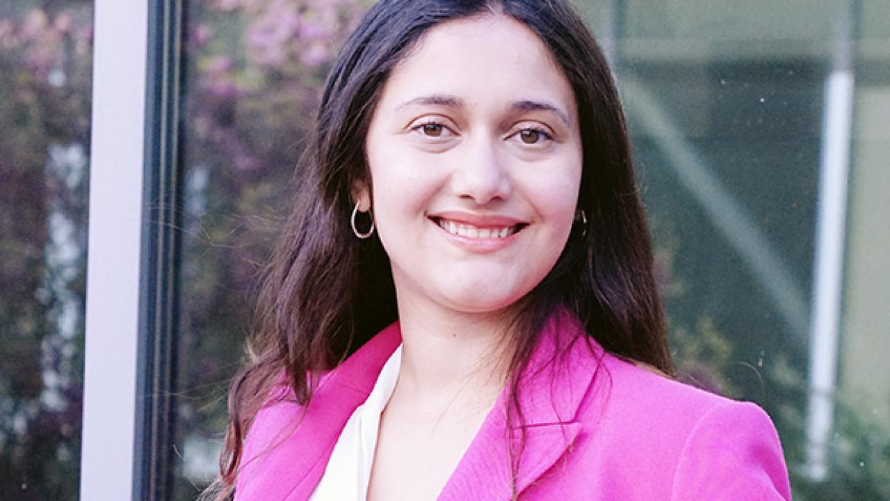 Carla-Cristina smiling with long dark hair wearing a pink blazer.