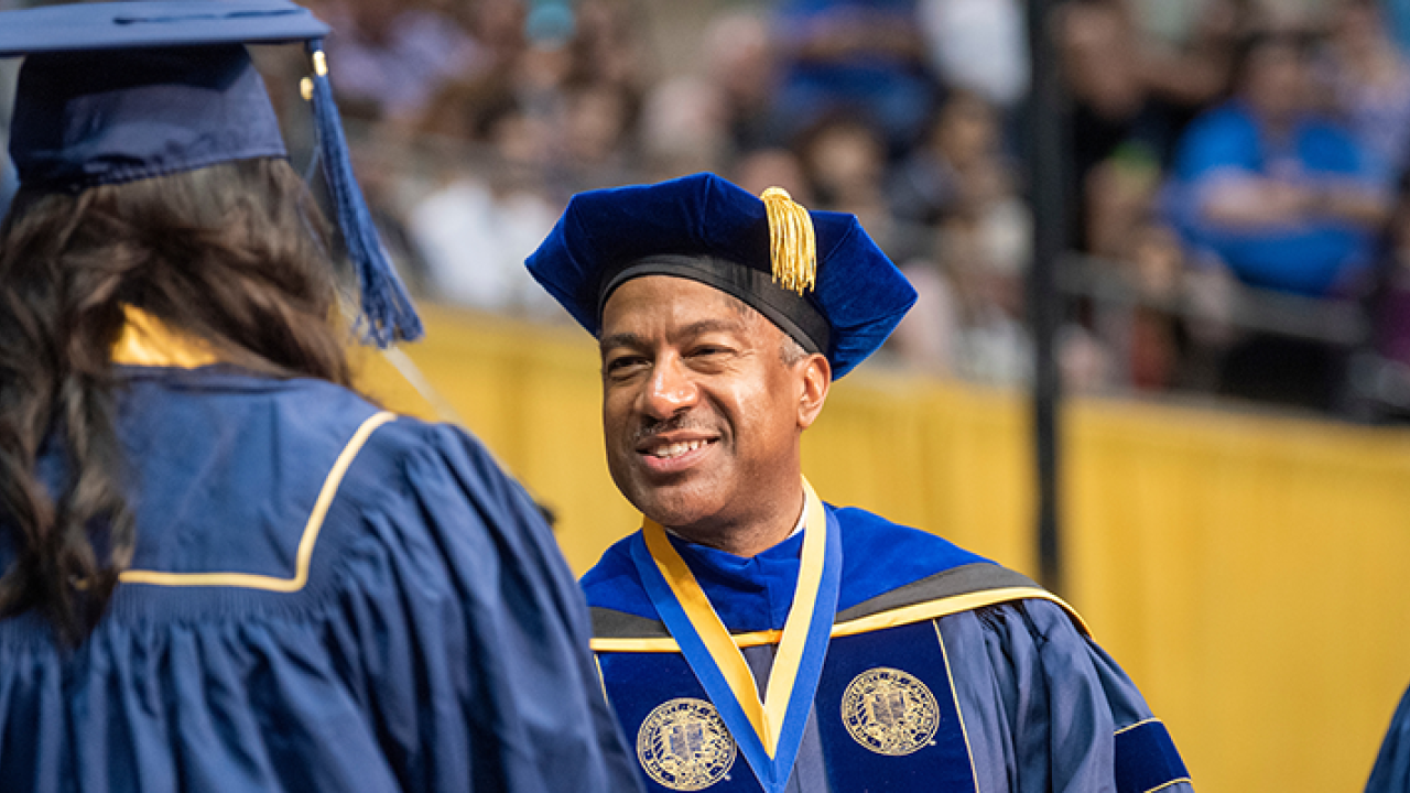 Photo of Chancellor May handing a degree to a student at Commencement 
