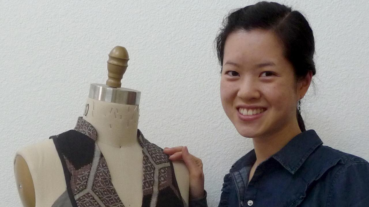 Carol Shu smiling next to her clothing design.