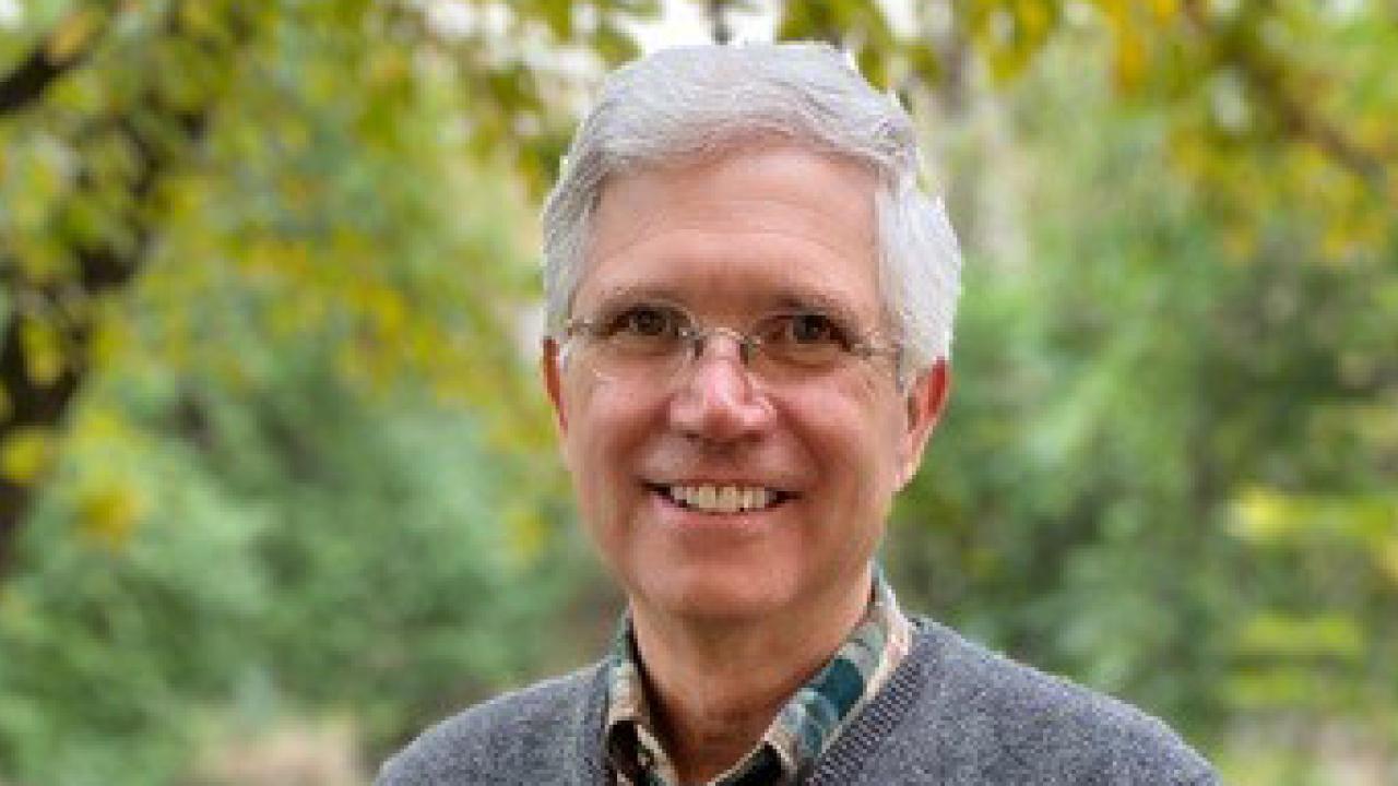 Alumnus David Loury in front of trees