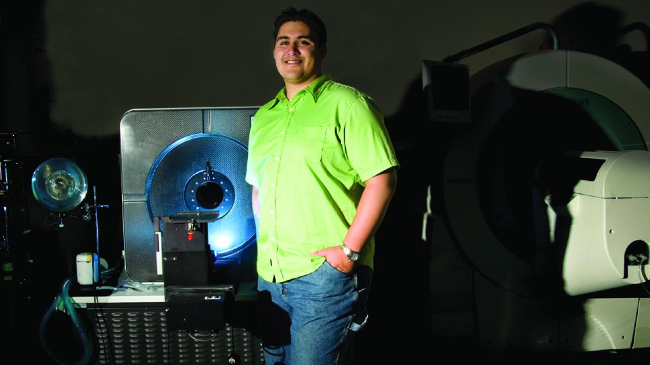 Felipe Godinez at the GBSF building standing next to a scanning medical device.
