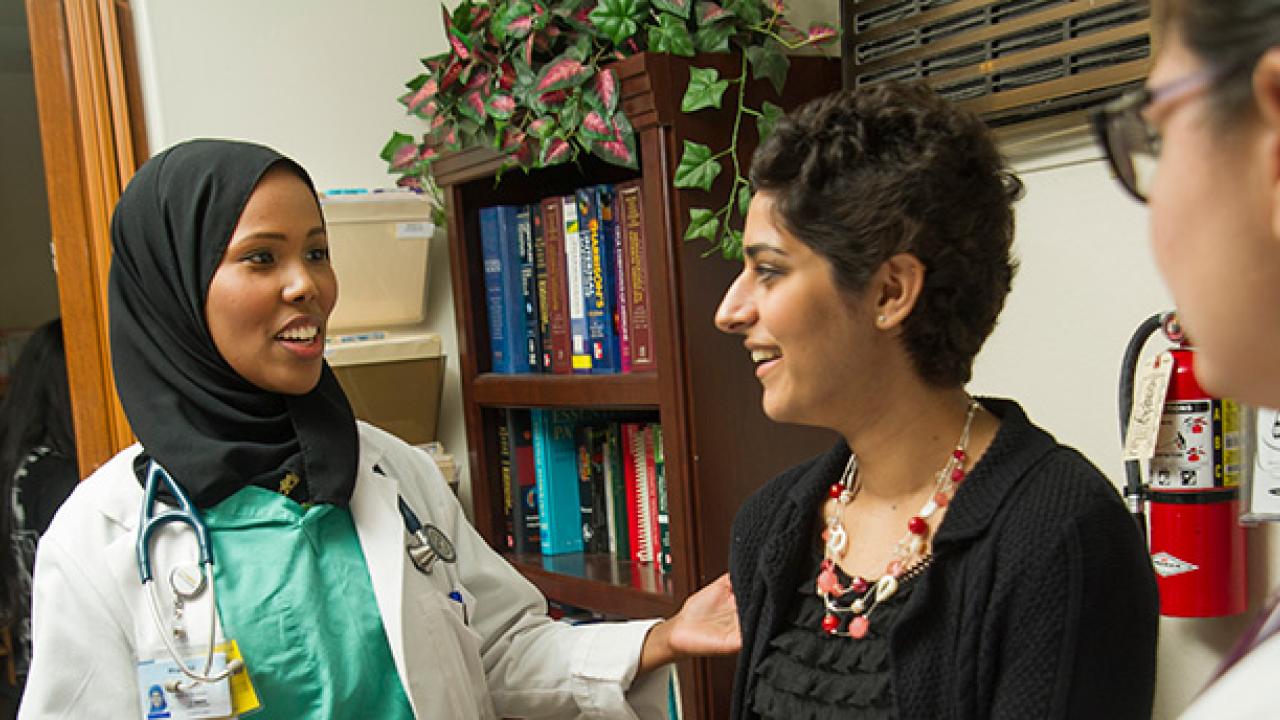 Medical students Ifrah Ali, left, and Talin Arslanian, right, chat with a chats with an undergraduate volunteer, Simirin Atwal, during their shift at the Shifa Community Clinic in downtown Sacramento. (Karin Higgins/UC Davis)