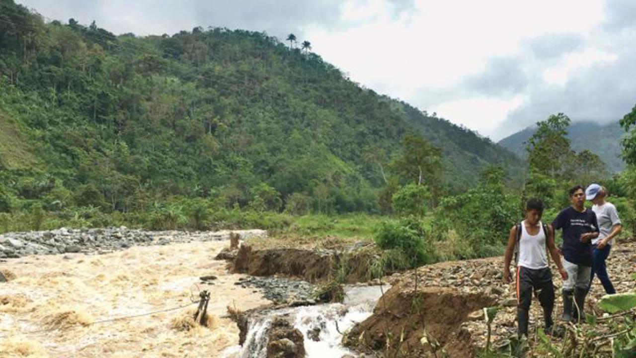 Dulcepamba Project team members Rachel Conrad, Darwin Paredes, and his son, Jairo Parades, observe how the Dulcepamba River relocated to the only road out of San Pablo de Amalí. Downed power lines are in rapids where the road had been. Credit: