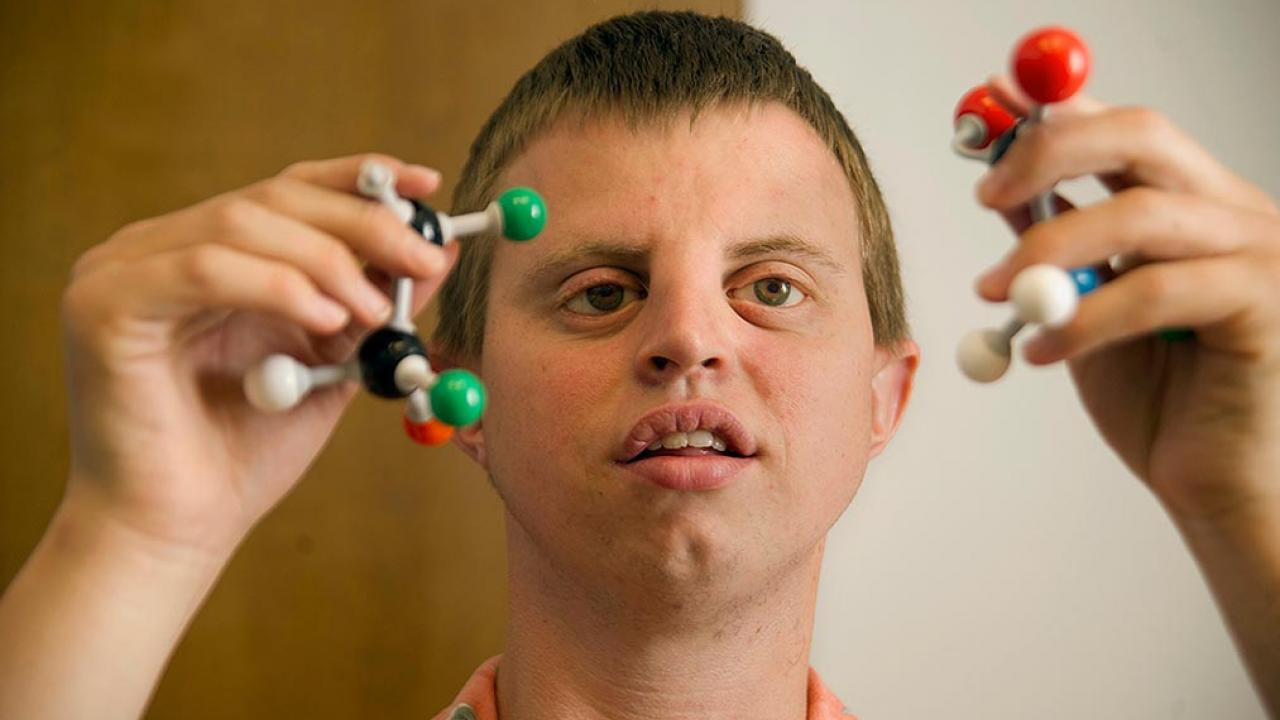 Hoby Wedler holding three-dimensional models of atoms.