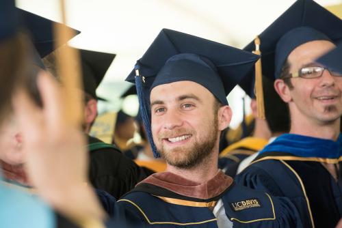 Students wearing academic regalia with brown and blue silks signifying different academic specialties. 