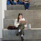 Students sitting on stairs looking at computers.