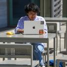 Student at table looking at computer.