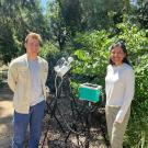 Kyle Rizzo and Alejandra Ponce de Leon smile next to scientific equipment outside on a sunny day in the Arboretum.