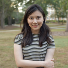 Nalina Aiempichitkijkarn smiles at camera with arms crossed and wearing a black and white stripped shirt.