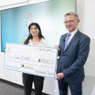 Yara Khatib smiling with giant check next to Dean Jean-Pierre Deplanque.