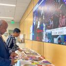 UC Davis Chancellor Gary S. May and LeShelle May interact with a colorful art exhibit in the lobby of the International Center.