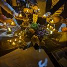 photo of multiple people holding candles in a circle around a table with flowers
