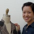 Carol Shu smiling next to her clothing design.