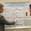 Graduate student explains her poster to another student.