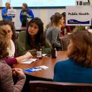 Graduate students and postdocs talk with a career specialist at the Public Health table.